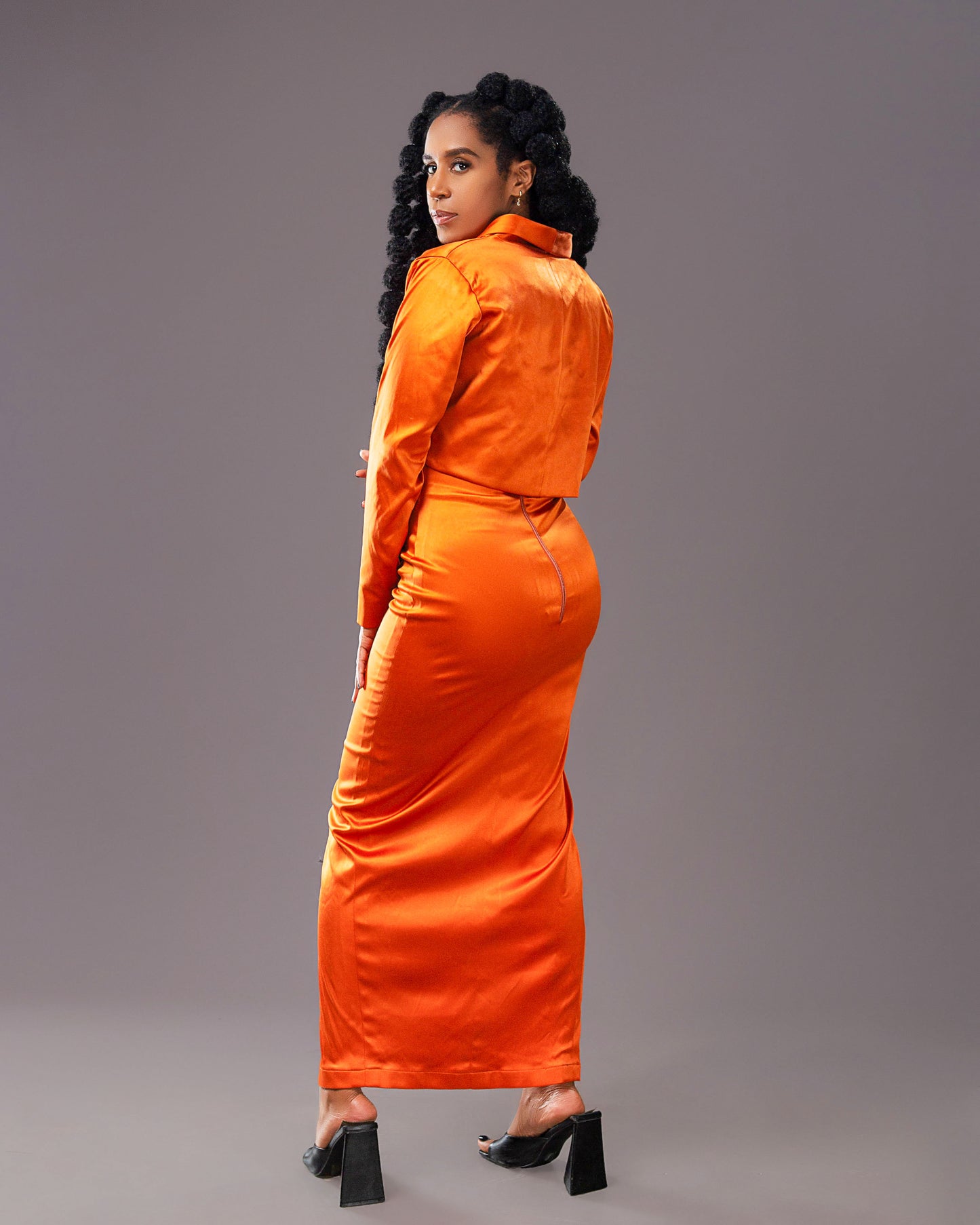 A woman wearing a stylish orange maxi skirt with matching long-sleeved coat like top