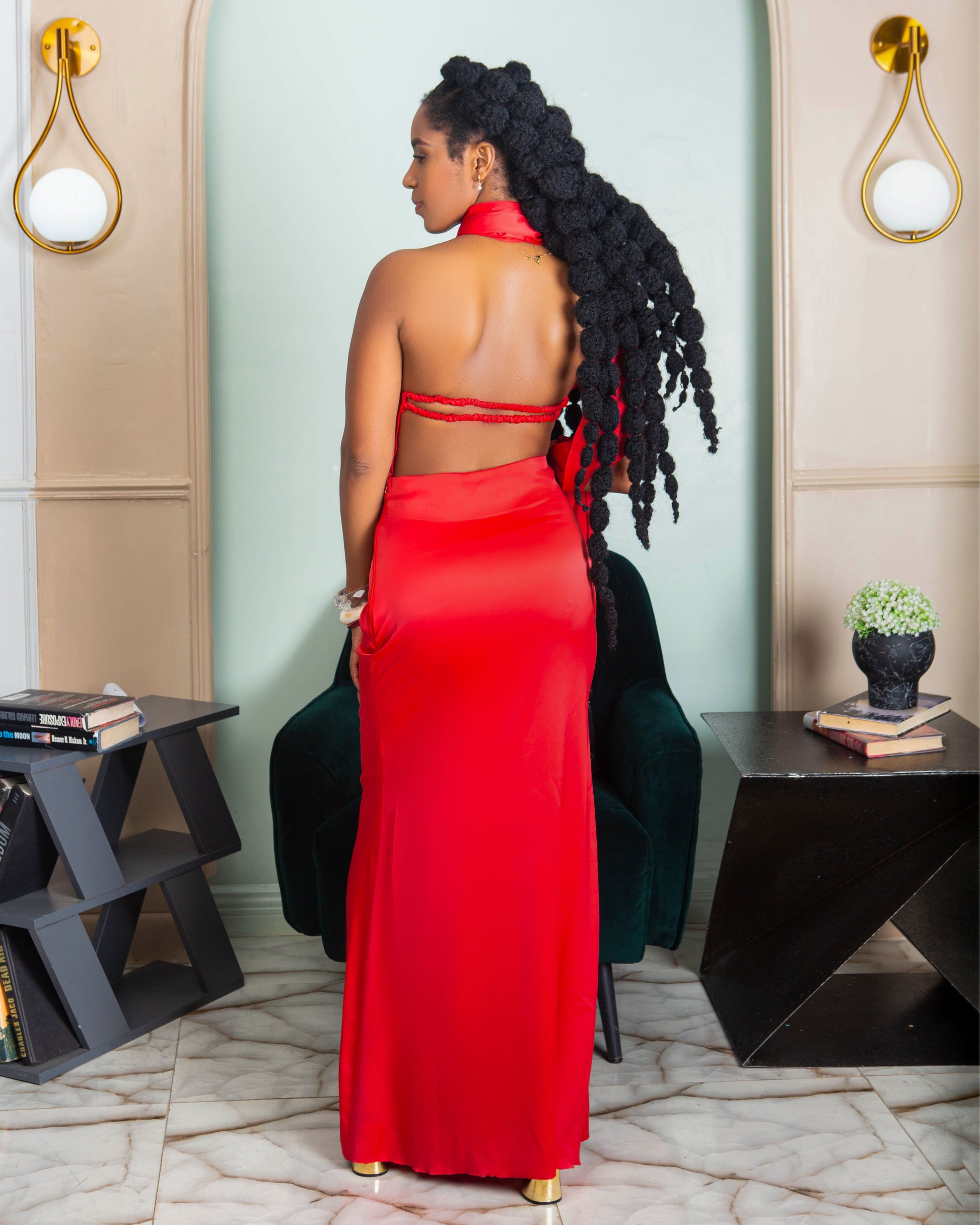 A beautiful woman wearing a red halter neck maxi dress with open back