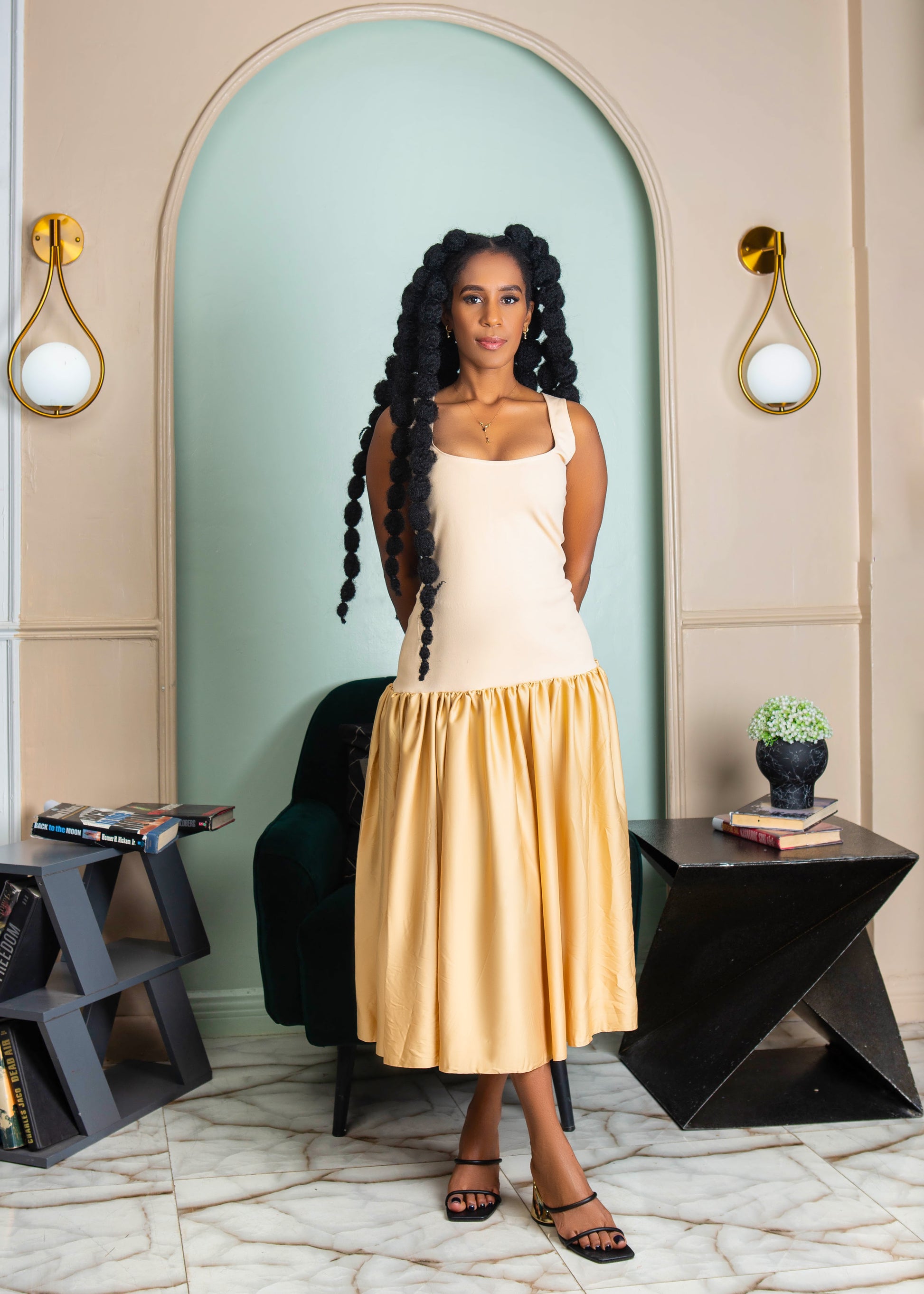 A beautiful woman wearing a beige sleeveless midi dress with gathered waist