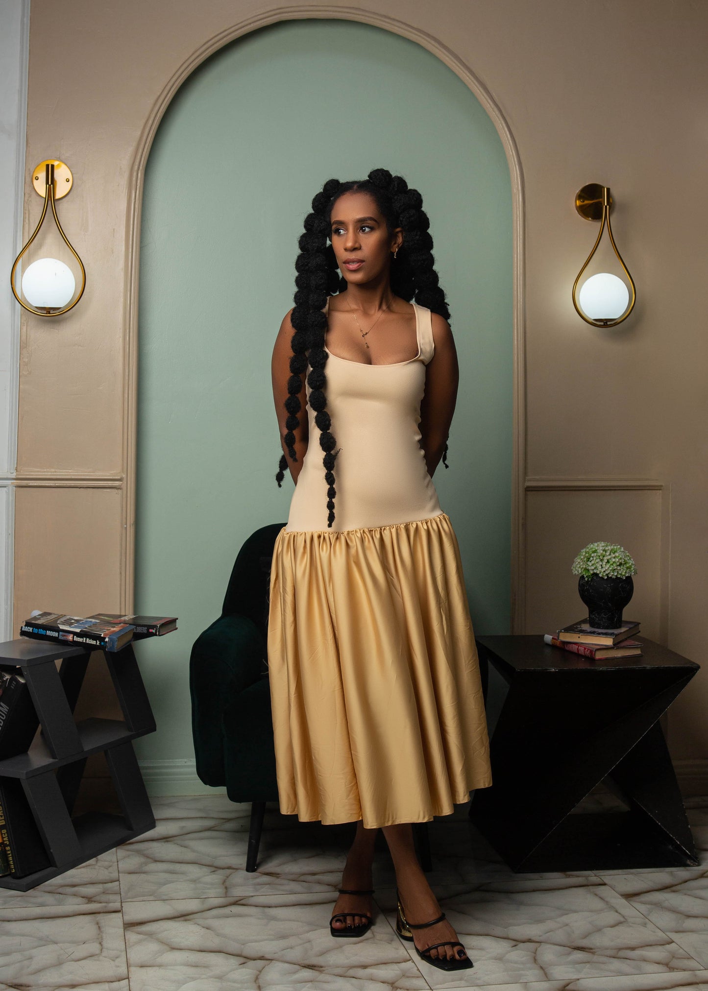 A beautiful woman wearing a beige sleeveless midi dress with gathered waist