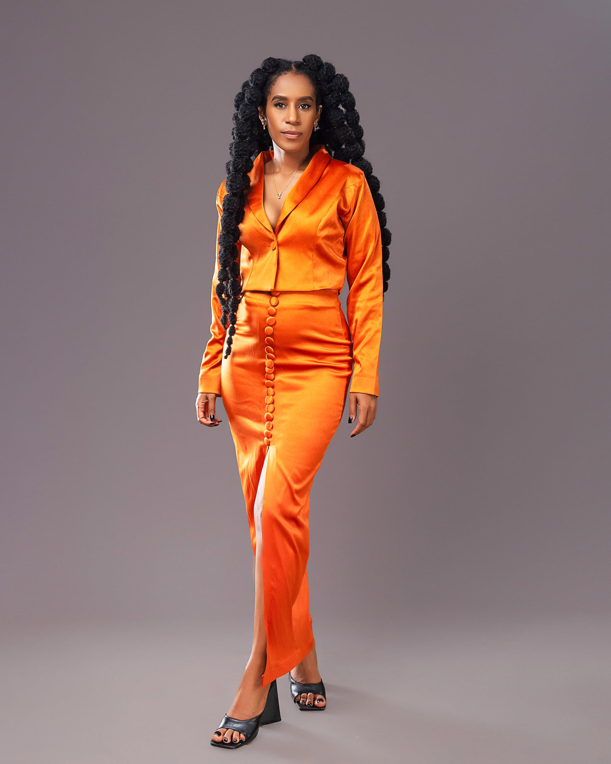 A woman wearing a stylish orange maxi skirt with matching long-sleeved coat like top