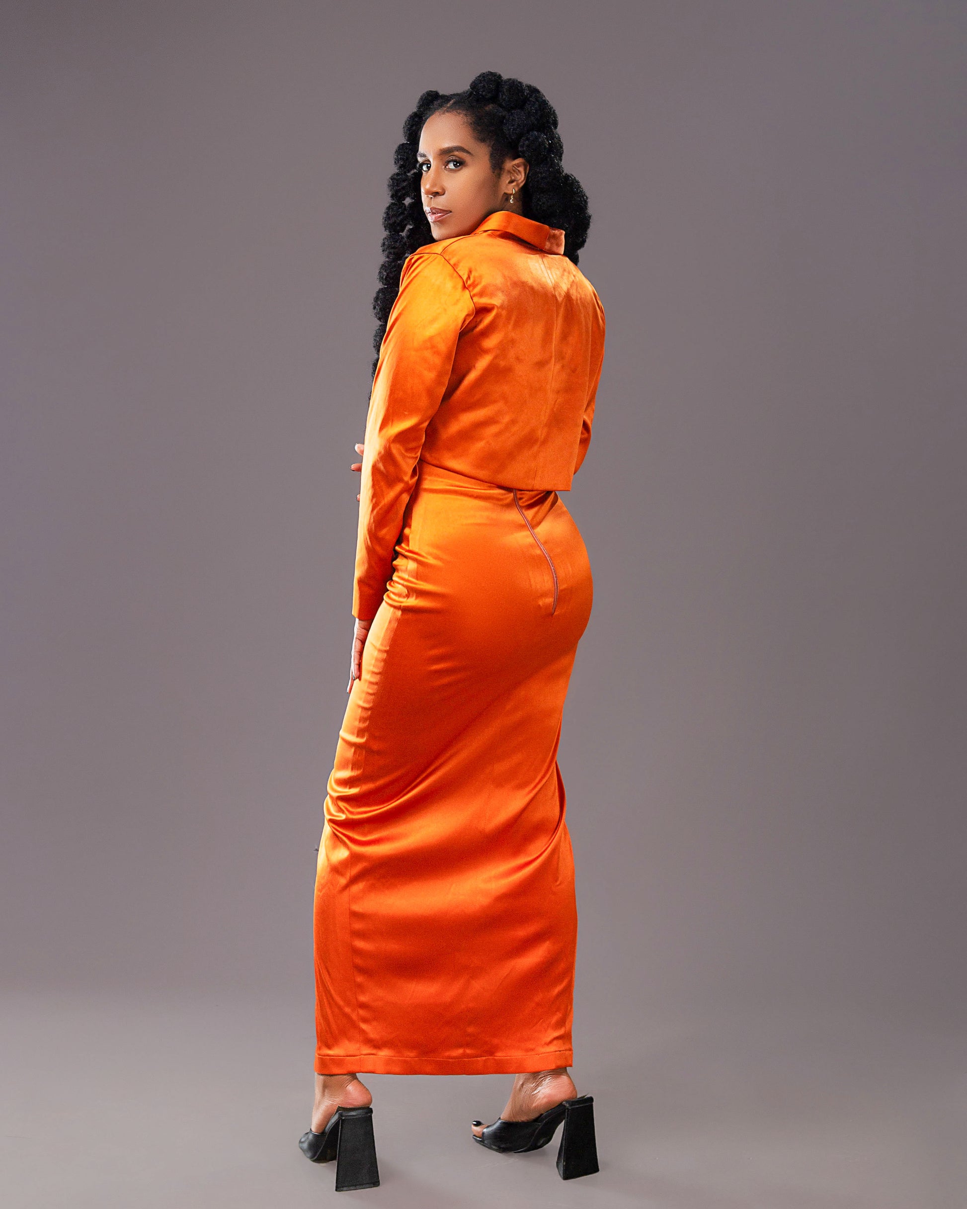 A woman wearing a stylish orange maxi skirt with matching long-sleeved coat like top